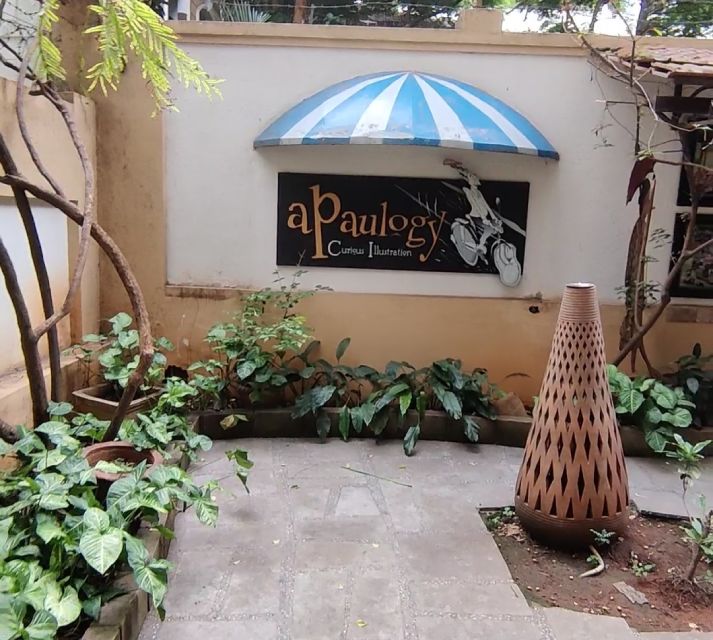 A name board of an art gallery surrounded by plants and a huge pot